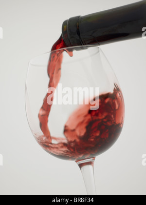 Red wine pouring into grass, close up, white background Stock Photo