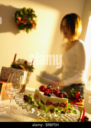 Christmas cake on table, woman holding plates in background, blurred motion Stock Photo