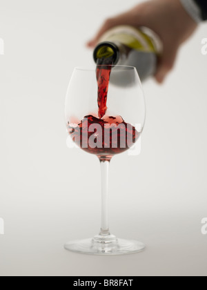 Red wine pouring into grass, close up, white background Stock Photo