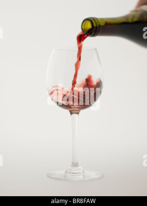 Red wine pouring into grass, white background Stock Photo