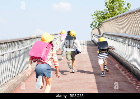 Elementary school students running to school, rear view Stock Photo