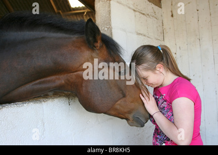 Teenage girl leaning her head against a horse's head Stock Photo