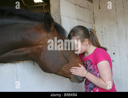 Teenage girl leaning her head against a horse's head Stock Photo