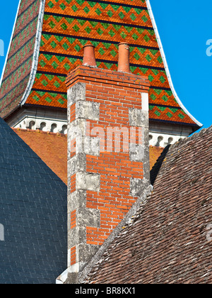 Old chimney stack and decorative, slated and tiled roofs  - France. Stock Photo