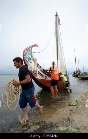 Fishermen pull a traditional Moliceiro boat near Aveiro, Portugal Stock Photo