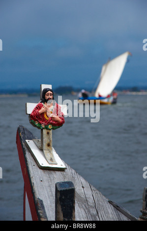 Cross with Jesus Christ  on a traditional Moliceiro boat bow with an out-of-focus Moliceiro boat in the background, Portugal Stock Photo