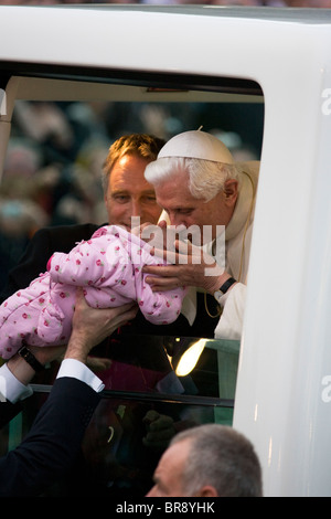 With Georg Gänswein, Pope Benedict XVI kisses a baby lifted up to his open car window as he arrives in Popemobile at Hyde Park. Stock Photo