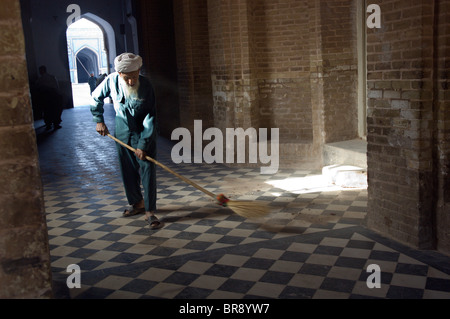 An elderly man sweeps a corridor in the Friday Mosque or Stock Photo