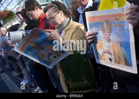 Catholics read free newspapers to crowds outside Westminster Cathedral before Pope Benedict XVI arrives. Stock Photo