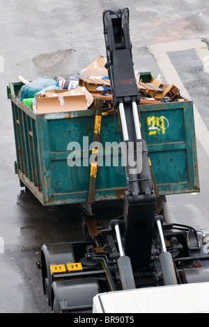 Rubbish clearance, the lifting and loading of a large skip full of waste Stock Photo