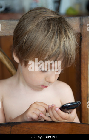 young boy playing ben 10 game on an iphone in ibiza, spain Stock Photo