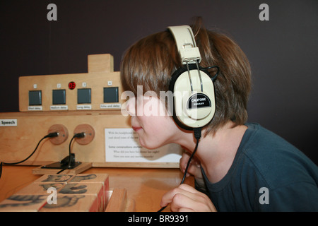 Child having fun experimenting with wave forms and speech sounds, wearing headphones Stock Photo