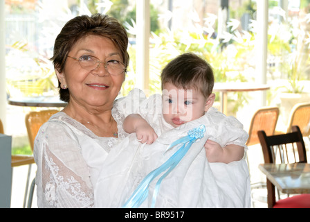 Merida, Yucatan/Mexico-July 8:Baby boy baptism celebration. Grandmother holding Boy wearing traditional ceremonial loose gown clothing Stock Photo