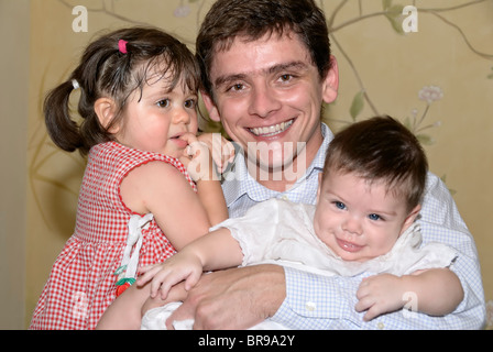 Merida, Yucatan/Mexico-July 8: Baby boy baptism celebration. Father holding in arms his baby boy and a guest girl, smiling Stock Photo