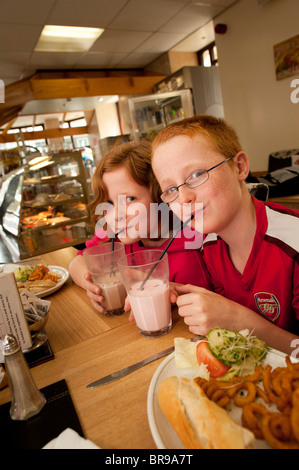 Eleven year old twin brother and sister drinking milkshakes in he soon the close National Milk Bar, Aberystwyth Wales UK Stock Photo