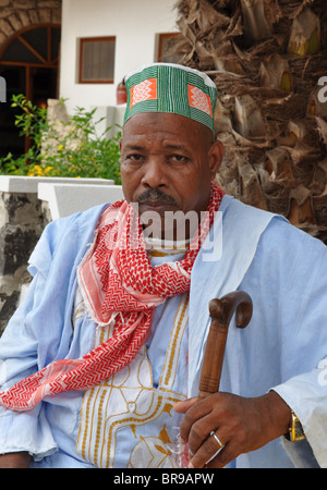 A local man in traditional dress clothing walks along colourful Stock ...