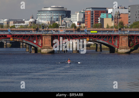 Rowers training on the River Clyde travelling west towards the Pipe Bridge and Tidal Weir in Glasgow, Scotland, UK Stock Photo