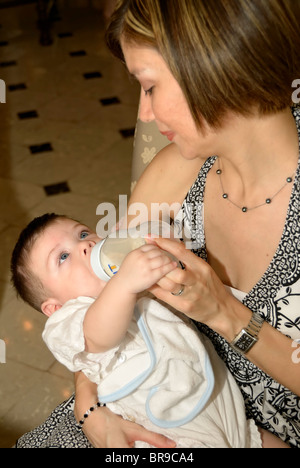 Merida, Yucatan/Mexico-July 8:Baby boy baptism celebration. Mother bottle feeding milk to her son Stock Photo