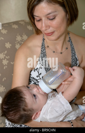 Merida, Yucatan/Mexico-July 8:Baby boy baptism celebration. Mother bottle feeding milk to her son Stock Photo