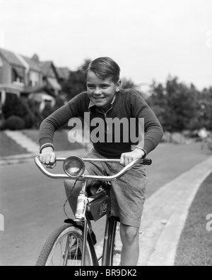 1930s SMILING BOY RIDING BICYCLE Stock Photo