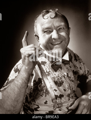 1930s SMILING CHARACTER MAN WITH TWO SPIT CURLS ON FOREHEAD POINTING INDEX FINGER Stock Photo