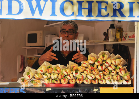 A sandwich stall owner smiling and pointing at his sandwiches Stock Photo