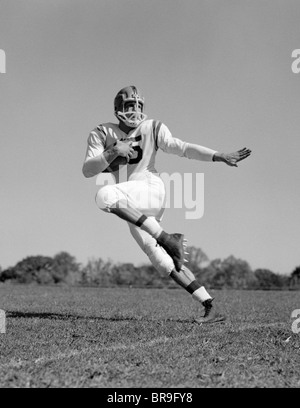 1960s YOUNG MAN FOOTBALL PLAYER RUNNING WITH BALL Stock Photo