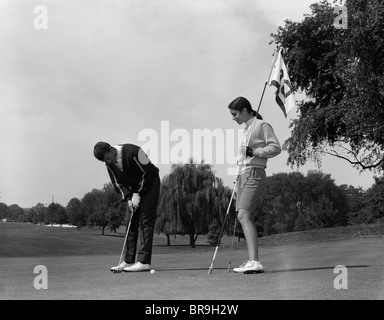 1960s COUPLE MAN WOMAN PUT PUTTING Stock Photo