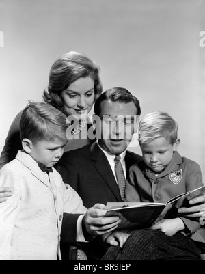 1960s FAMILY FATHER MOTHER SONS READING BOOK TOGETHER Stock Photo