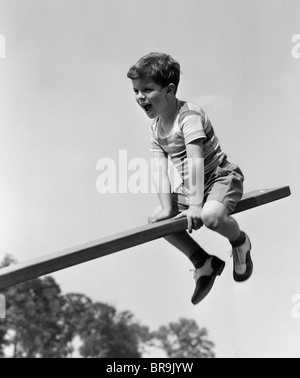 1930s 1940s EXCITED BOY ON SEESAW PLAYING Stock Photo