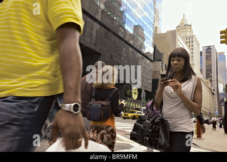 Woman walking across street while operating hand-held device. Stock Photo