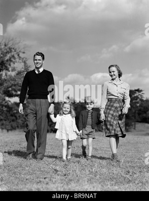 1940s FAMILY HOLDING HANDS WALKING ON GRASS Stock Photo