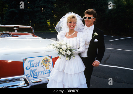 1991 BRIDE AND GROOM STANDING NEXT TO VINTAGE CONVERTIBLE FORD AUTOMOBILE Stock Photo