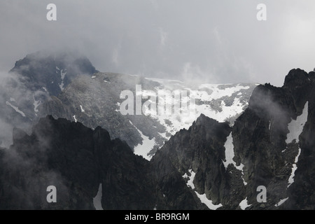 Rising mist low cloud swirls around Els Encantats peak viewed from d'Amitges in Sant Maurici National Park Pyrenees Spain Stock Photo