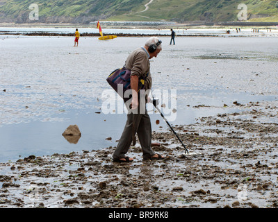 Man using metal-detector on the beach at low tide Stock Photo