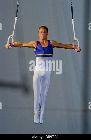 Male gymnast performing on the rings. Stock Photo