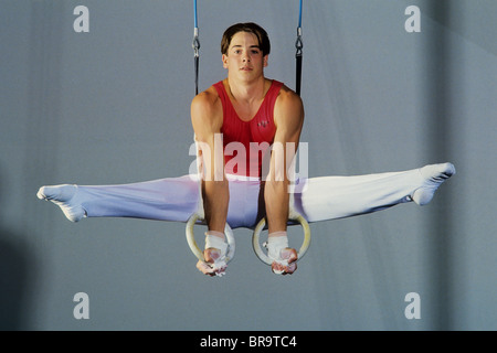 Male gymnast performing on the rings. Stock Photo