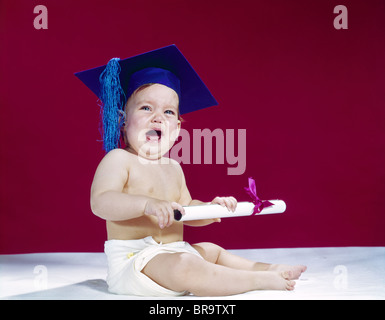 1960s CRYING BABY HOLDING DIPLOMA WEARING GRADUATION CAP Stock Photo