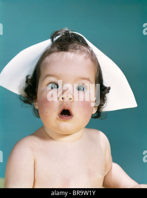 1960s SURPRISED BABY FACIAL EXPRESSION WEARING A NURSE CAP LOOKING AT CAMERA Stock Photo
