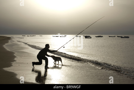 A man with his dog fishes at the mouth of the Gualdalquivir River Stock Photo