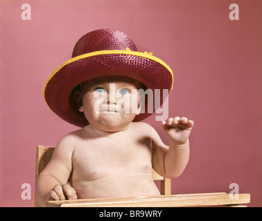 1960s BABY MAKING FACE WEARING RED STRAW HAT Stock Photo