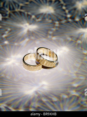 TWO GOLD WEDDING RING BANDS ON A PATTERNED BACKGROUND Stock Photo