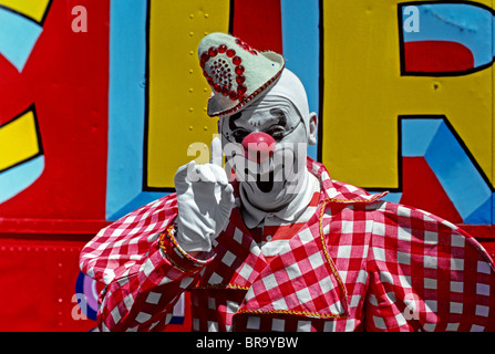 1970s WHITE FACED CLOWN IN RED CHECKED JACKET HOLDING UP GLOVED HAND Stock Photo