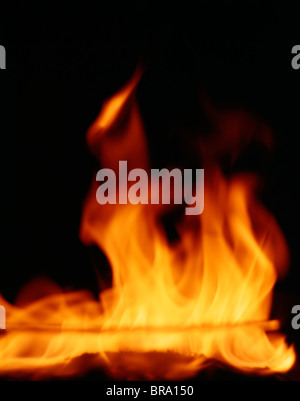 DETAIL OF ORANGE RED FLAMES OF A FIRE AGAINST BLACK BACKGROUND Stock Photo