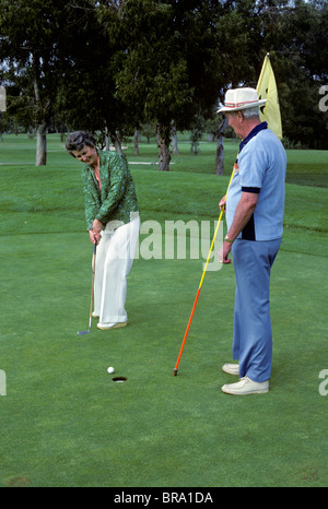 1980s SENIOR MAN & WOMAN PLAYING GOLF Stock Photo
