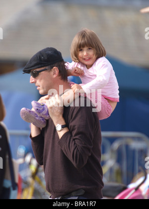 Young child being carried on her fathers shoulders, looking scared, Devon, UK Stock Photo