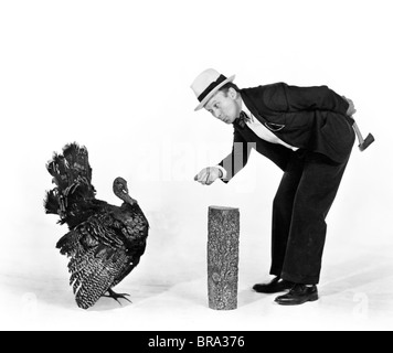 1930s 1940s MAN CHARACTER WITH HATCHET TRYING TO CATCH A THANKSGIVING TURKEY Stock Photo