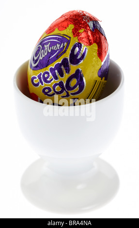 cadburys creme egg in a white egg cup on white background Stock Photo