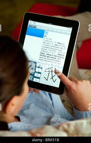 Woman using iPad tablet computer at home to study Chinese language using self study education application Stock Photo