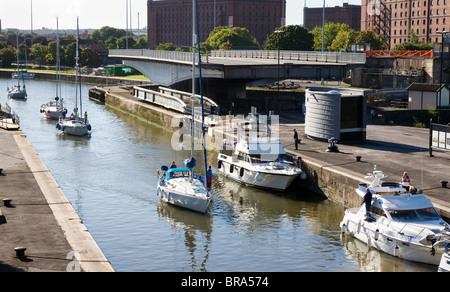 Sailing boats enter the Brunel lock from the Cumberland basin Bristol with the Plimsoll swing bridge open to admit their masts Stock Photo